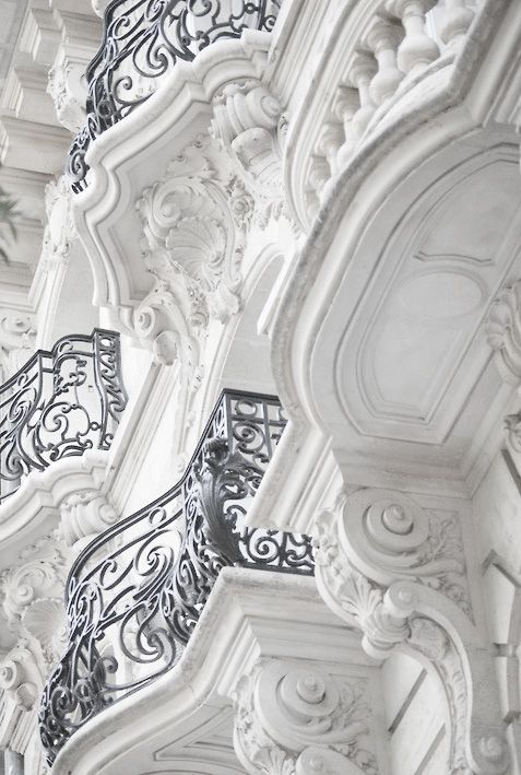 rows of ornate cast iron balconies on the side of a building in a french town
